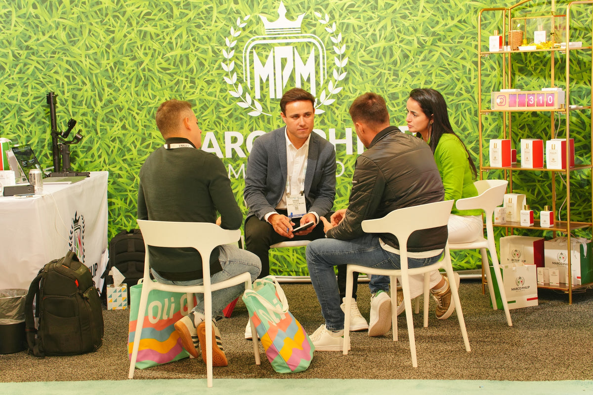 The Marco Philip Milano booth at Cosmoprof North America Miami 2025, with the brand crest on a wall of green foliage